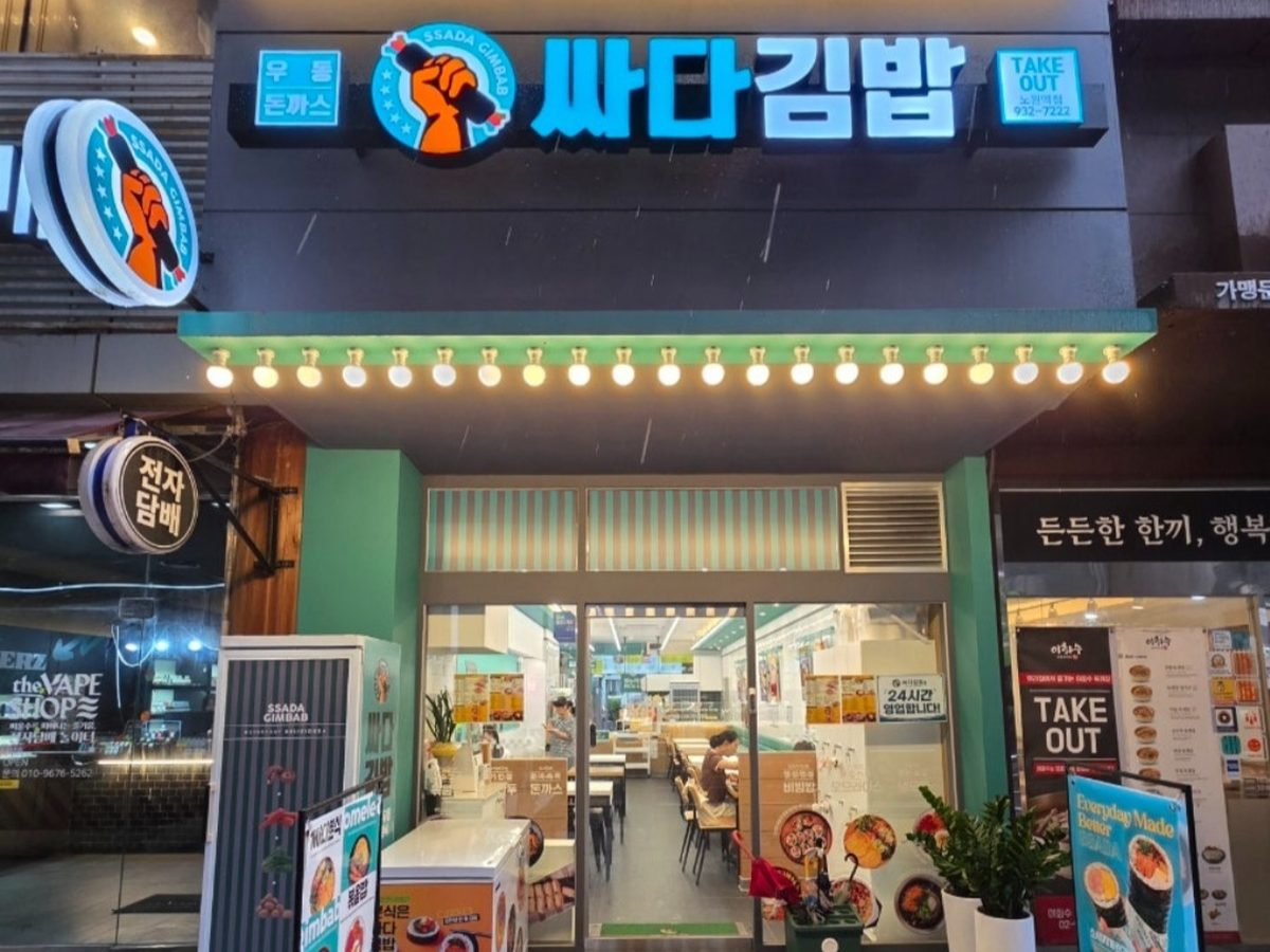 싸다김밥 노원역점 매장 외부 야간. 서울 노원구 상계로 55 상가 1층 103호, 파란 간판에 우동·돈까스 표기와 TAKE OUT 전화번호 02-932-7222.
