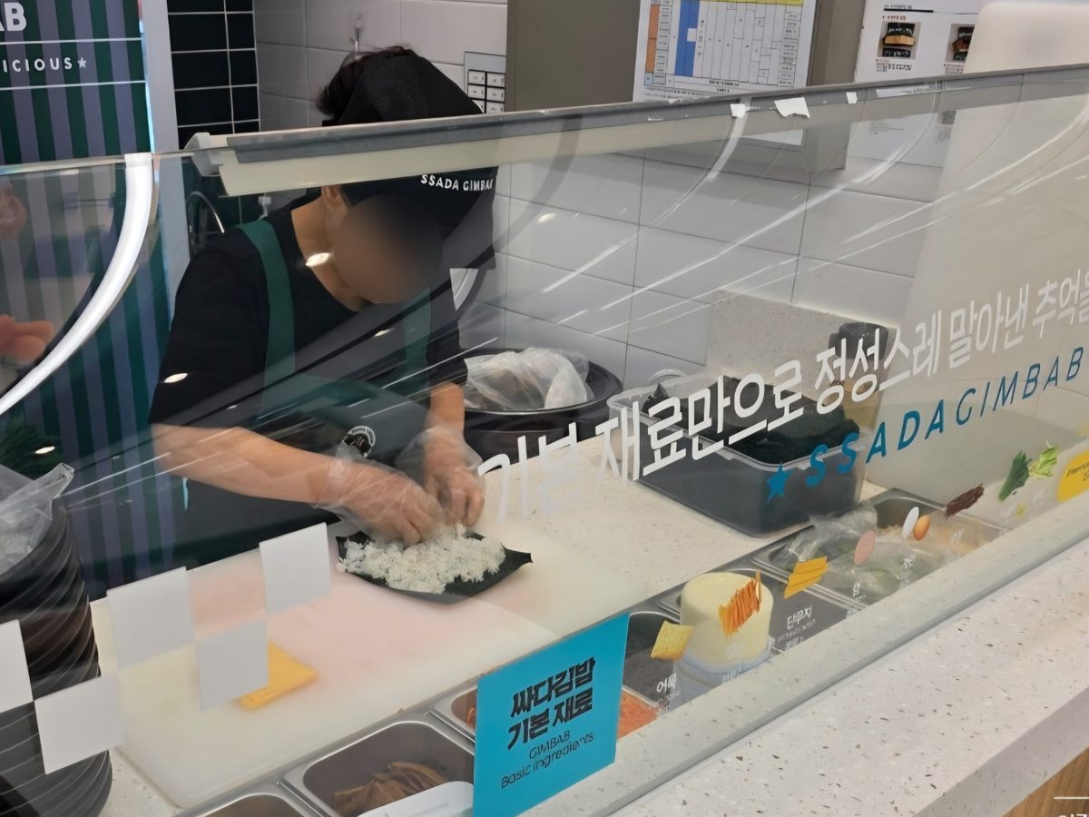 주문 후 김밥을 말고 있는 조리대. 김 위에 밥을 펴고 있으며 옆에는 단무지·당근·계란 등 기본 재료가 준비되어 있다.
